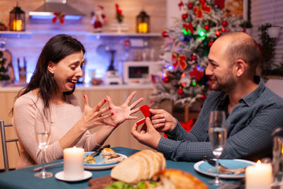 Happy man proposing woman at home against christmas tree