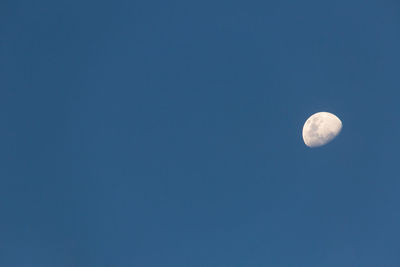 Low angle view of moon against blue sky