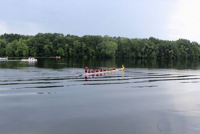 People on boat in lake against sky