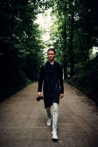 Full length portrait of young man walking on footpath in forest