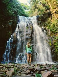 Woman standing by waterfall in forest