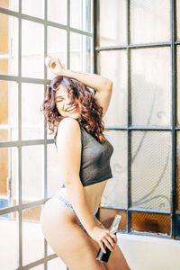 Beautiful woman laughing while standing against window