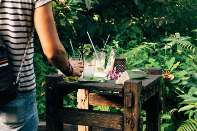 Midsection of woman standing by flower plants in yard