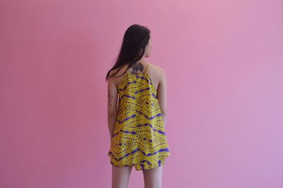 Rear view of woman standing against pink background