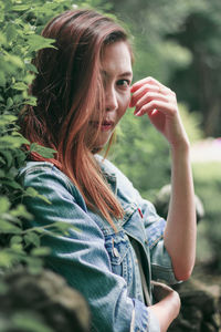 Portrait of beautiful woman standing against plants in park