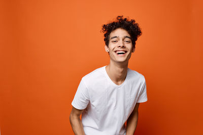 Portrait of smiling man standing against orange background