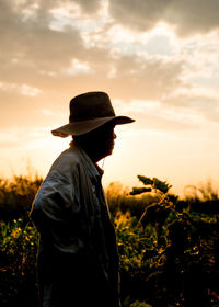 Man standing on field against sky during sunset