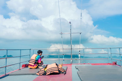 Man sitting on boat against sky