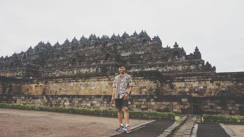 Full length portrait of young man standing outside temple