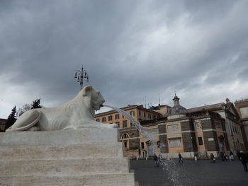 Statue by historic building against sky in city