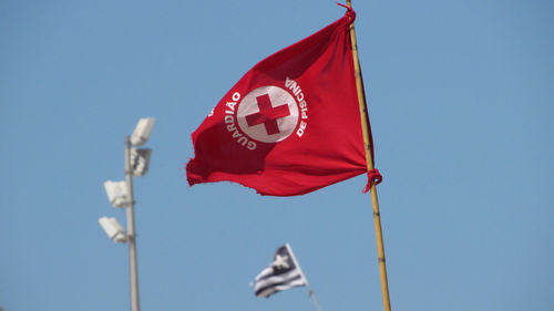 Low angle view of flag against clear blue sky