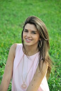 Portrait of smiling young woman sitting on grassy land