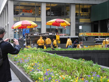 People standing by flowers in city