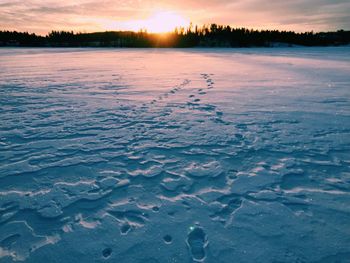 Scenic view of frozen lake against sky during sunset