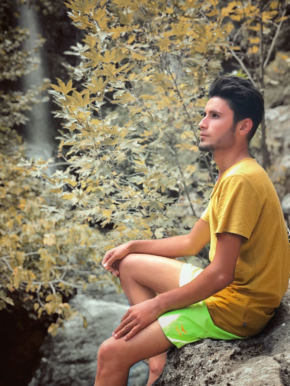 SIDE VIEW OF TEENAGE GIRL SITTING ON ROCKS