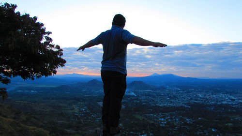 Rear view of man standing on mountain against sky