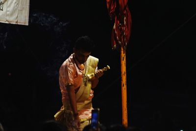 Rear view of man holding cross in temple at night