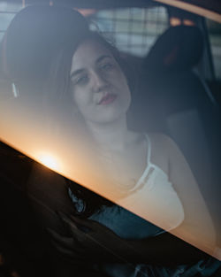 Portrait of young woman sitting on car through the window