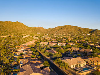 Houses amidst trees and buildings against clear sky