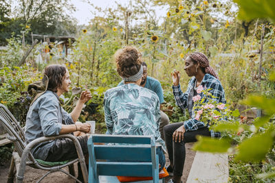 Male and female farmers having coffee while sitting in community garden