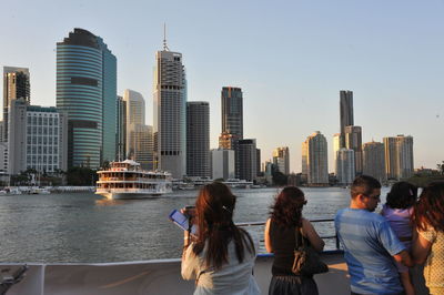 People on city buildings by sea against sky