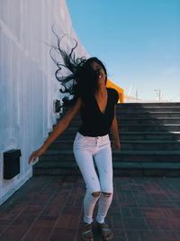 Full length of woman standing against staircase