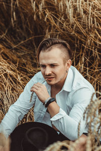 Young man looking away while sitting at farm