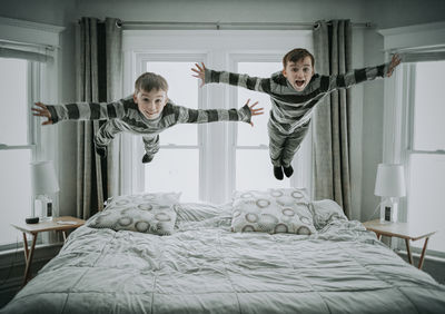 Portrait of boys jumping on bed in bedroom