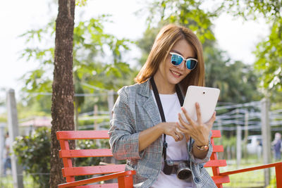 Portrait of young woman using mobile phone while sitting in park