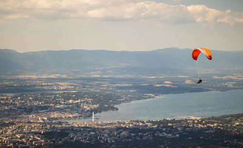 Person paragliding over landscape against sky