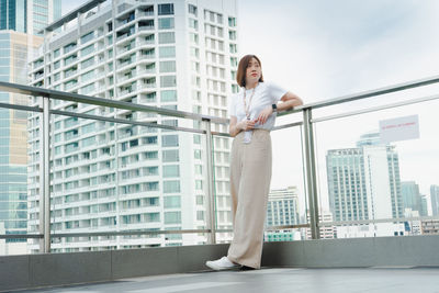 Solo asian woman during outdoor break and relax at rooftop with city background