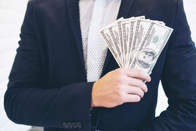 Midsection of man holding hands standing against wall