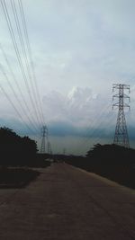 Electricity pylon by road against sky