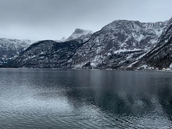 Scenic view of lake by snowcapped mountains against sky