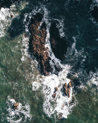 High angle view of ocean water flowing through rocks