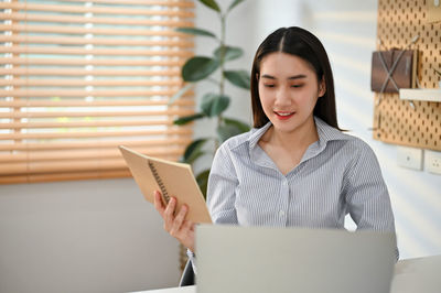 Portrait of young woman using laptop while sitting on table