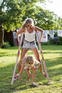 Sisters walking on stilts in garden