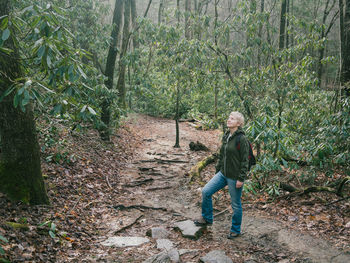 Full length of woman standing amidst trees in forest