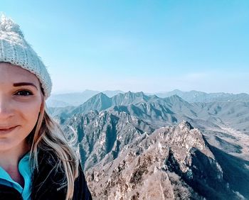 Portrait of woman with snowcapped mountains against sky during winter