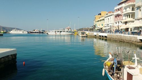 Sailboats moored in sea against clear blue sky