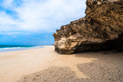 Rock formation on beach against sky