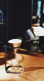 Close-up of hand holding wine glass on table