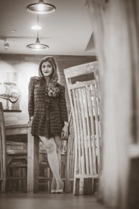 Portrait of young woman standing against wall