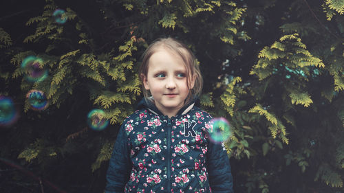 Portrait of smiling girl standing against trees