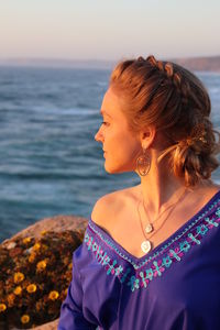 Midsection of woman by sea against sky during sunset