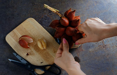 Cropped hands of woman holding lychee on table
