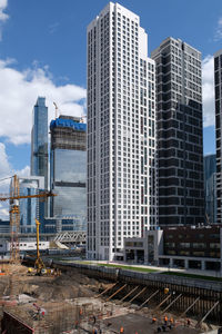 Construction site with foundation pit, machinery and worcers near of city skyscrapers