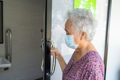 Side view of young woman washing hands in bathroom
