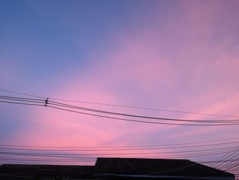 Low angle view of silhouette power lines against sky during sunset