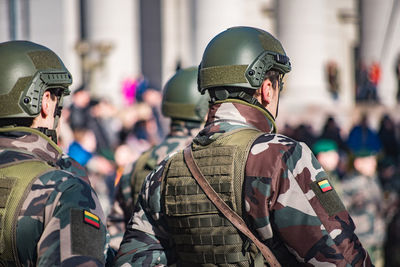 Rear view of army soldiers standing on street